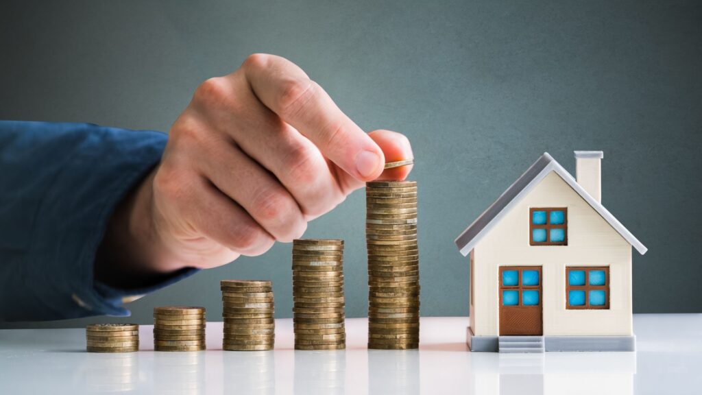 Stacks of coins next to a mini home, depicting increasing home values