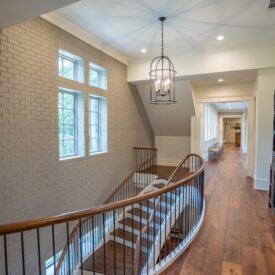 European style staircase with black iron balusters, wooden handrails and wooden treads.