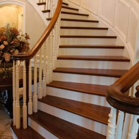 Curved staircase with stained wooden railings and treads, with white painted risers