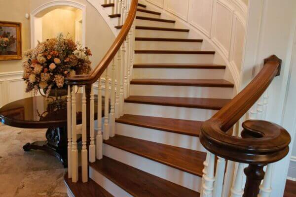Curved staircase with stained wooden railings and treads, with white painted risers